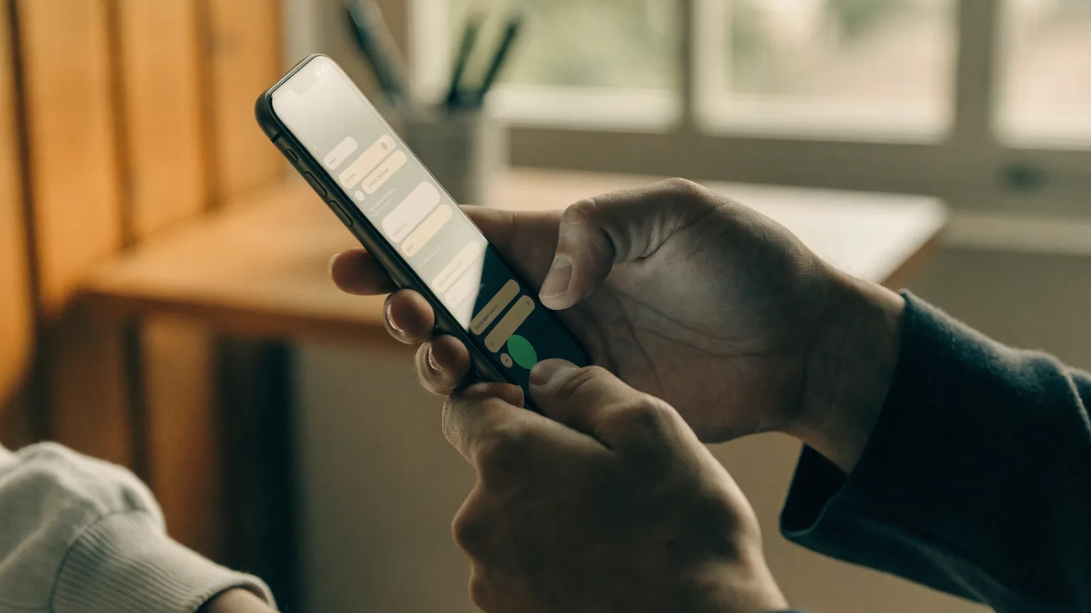 Mãos segurando um celular com uma enquete do WhatsApp aberta em um grupo, mostrando as opções de voto na tela