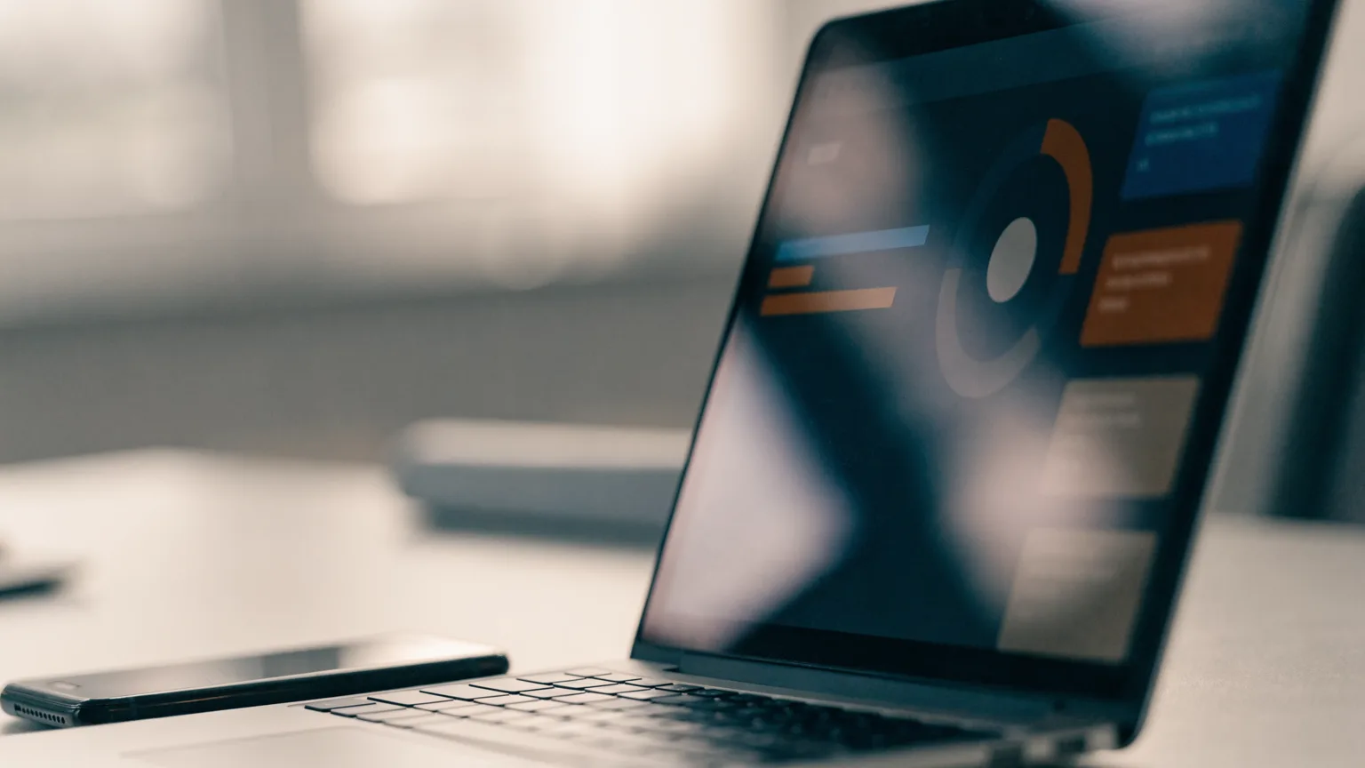 Notebook aberto com um painel de atendimento ao cliente e um celular ao lado, representando uma plataforma de WhatsApp
